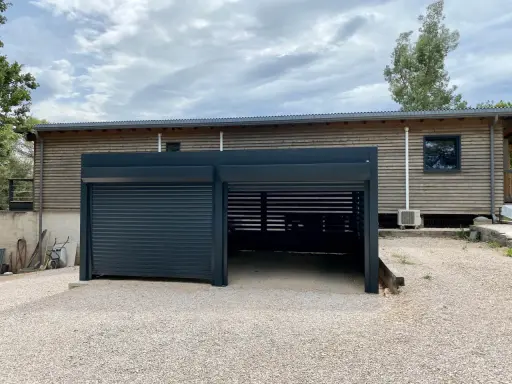 Abri voiture moderne avec un volet roulant fermé et une partie ouverte. Faut-il un permis de construire pour un abri voiture ouvert ?