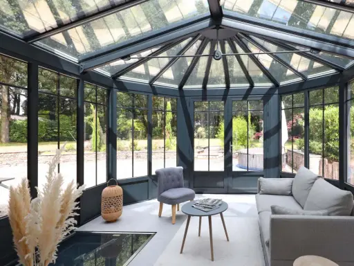 Une extension veranda moderne baignée de lumière, avec un salon confortable et une vue imprenable sur le jardin verdoyant.