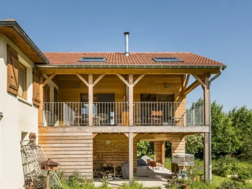 Extension en bois sur pilotis, avec balcon et terrasse aménagée. Une belle intégration architecturale.