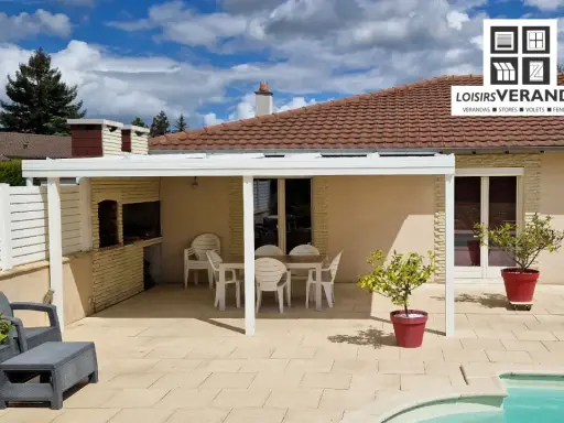 Un fabricant de pergolas a installé cette belle terrasse avec mobilier de jardin, barbecue et piscine.