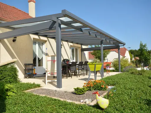 Superbe pergola Veranco avec toit vitré, aménagée pour les repas d'été. Avis très positif sur cette extension de maison.