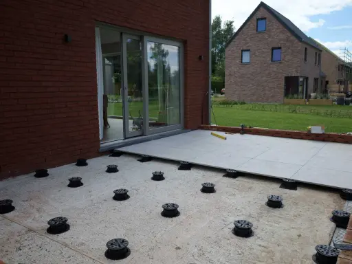 Installation de la dalle pour veranda sur des plots réglables. Le sol est en cours d'aménagement.