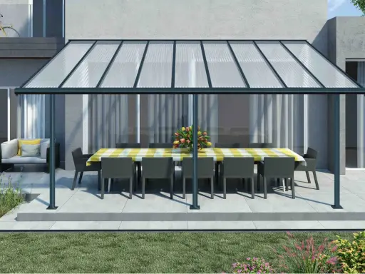 Une pergola canisse protège une table dressée et des fauteuils de la pluie, créant un espace extérieur accueillant.