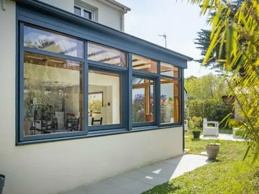 Belle extension cuisine sur jardin, avec de grandes baies vitrées offrant une vue imprenable sur la verdure et le soleil.