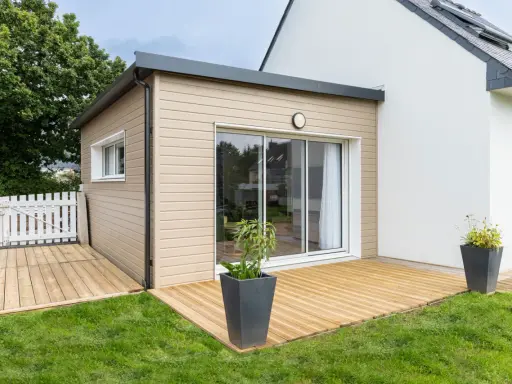 Une extension bois moderne avec terrasse en bois, créant un espace de vie extérieur agréable.