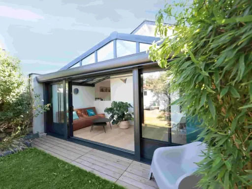 Une véranda sur terrasse sans fondation, avec un salon confortable et une vue sur le jardin verdoyant.