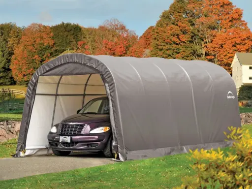 Voiture violette garée sous un carport démontable sans autorisation, dans un paysage d'automne.