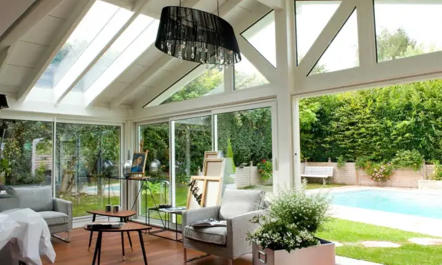 Plan de véranda à faire soi-même : une pièce lumineuse avec vue sur piscine, mobilier confortable et espace artistique.