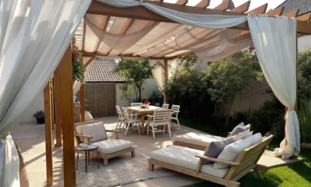 Une belle idée pergola jardin avec salon de jardin, chaises et table à manger, le tout sous des voilages légers.