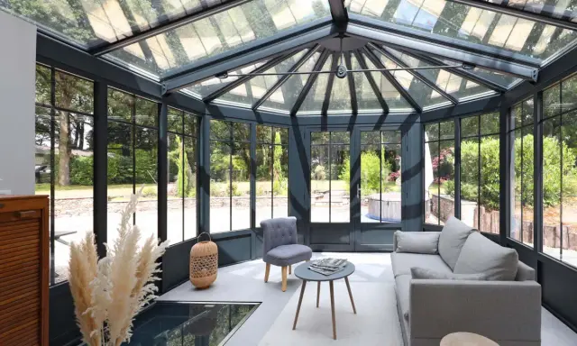 Une extension veranda moderne baignée de lumière, avec un salon confortable et une vue imprenable sur le jardin verdoyant.