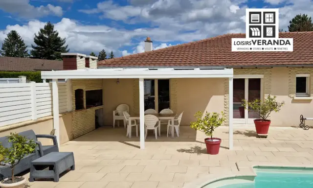 Un fabricant de pergolas a installé cette belle terrasse avec mobilier de jardin, barbecue et piscine.
