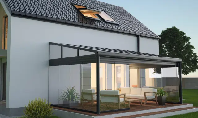 Une élégante veranda hexagonale en verre et métal, avec un salon confortable, s'intègre parfaitement à une maison moderne.