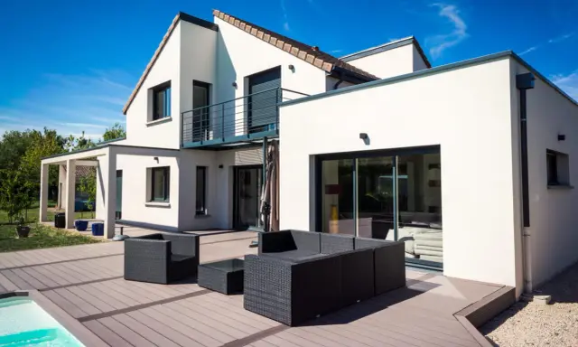 Une maison moderne avec une extension spacieuse, une terrasse en bois et une piscine. L'ensemble évoque une transformation réussie : extension maison avant après.