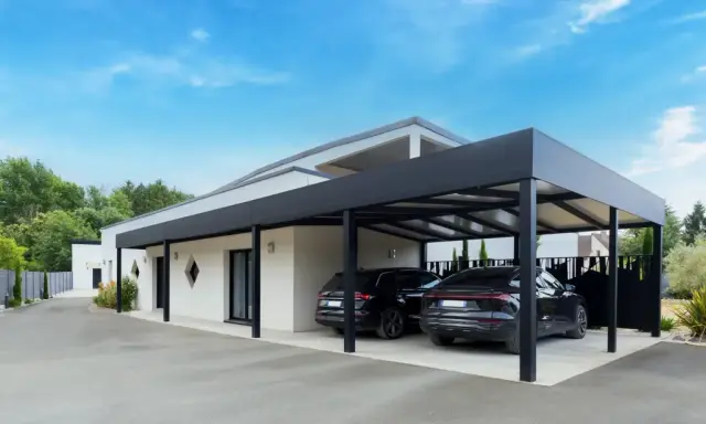 Deux voitures noires garées sous un carport moderne. Le propriétaire a décidé de fermer un carport sans autorisation, créant un espace de stationnement élégant.