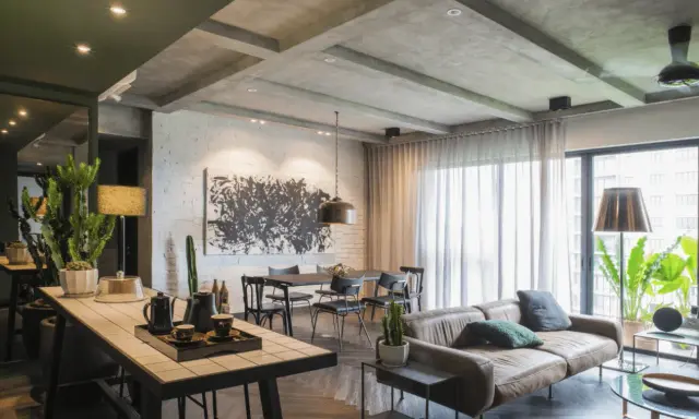 Un agrandissement salon moderne avec un canapé en cuir, une table à manger, une grande œuvre d'art abstraite et des plantes vertes.
