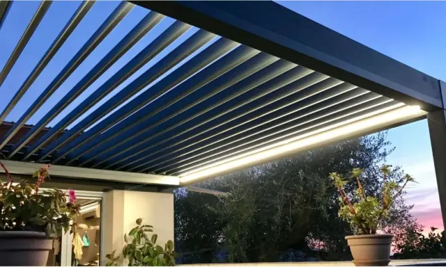 Pergola bioclimatique moderne avec lames parallèles, éclairage LED intégré, créant une ambiance douce au crépuscule.