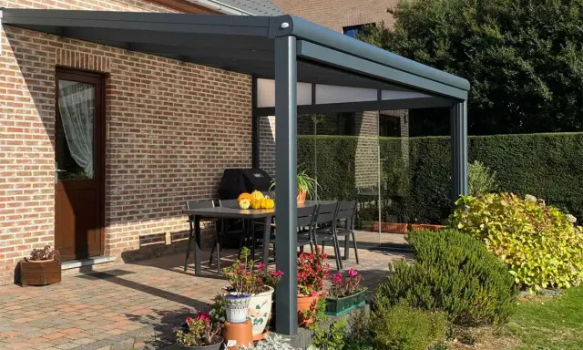 Terrasse avec pergola moderne, table et chaises. Le calcul prise au vent pergola est essentiel pour sa stabilité.
