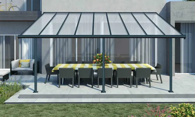 Une pergola canisse protège une table dressée et des fauteuils de la pluie, créant un espace extérieur accueillant.