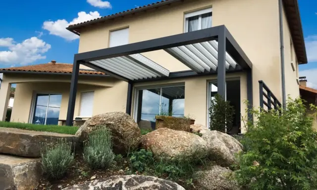 Pergola moderne sur terrasse avec vue sur une maison et un jardin rocheux.