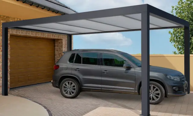 Une voiture grise est garée sous un tva carport moderne, à côté d'un garage.