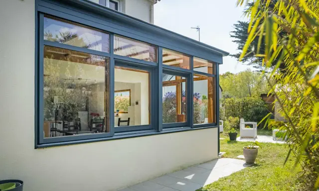 Belle extension cuisine sur jardin, avec de grandes baies vitrées offrant une vue imprenable sur la verdure et le soleil.
