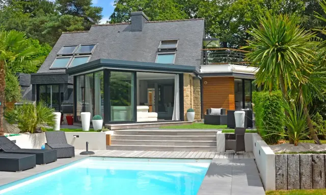 Maison moderne avec véranda et piscine. Pensez à comment déclarer une véranda aux impôts pour optimiser votre situation.