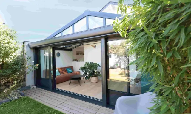 Une véranda sur terrasse sans fondation, avec un salon confortable et une vue sur le jardin verdoyant.