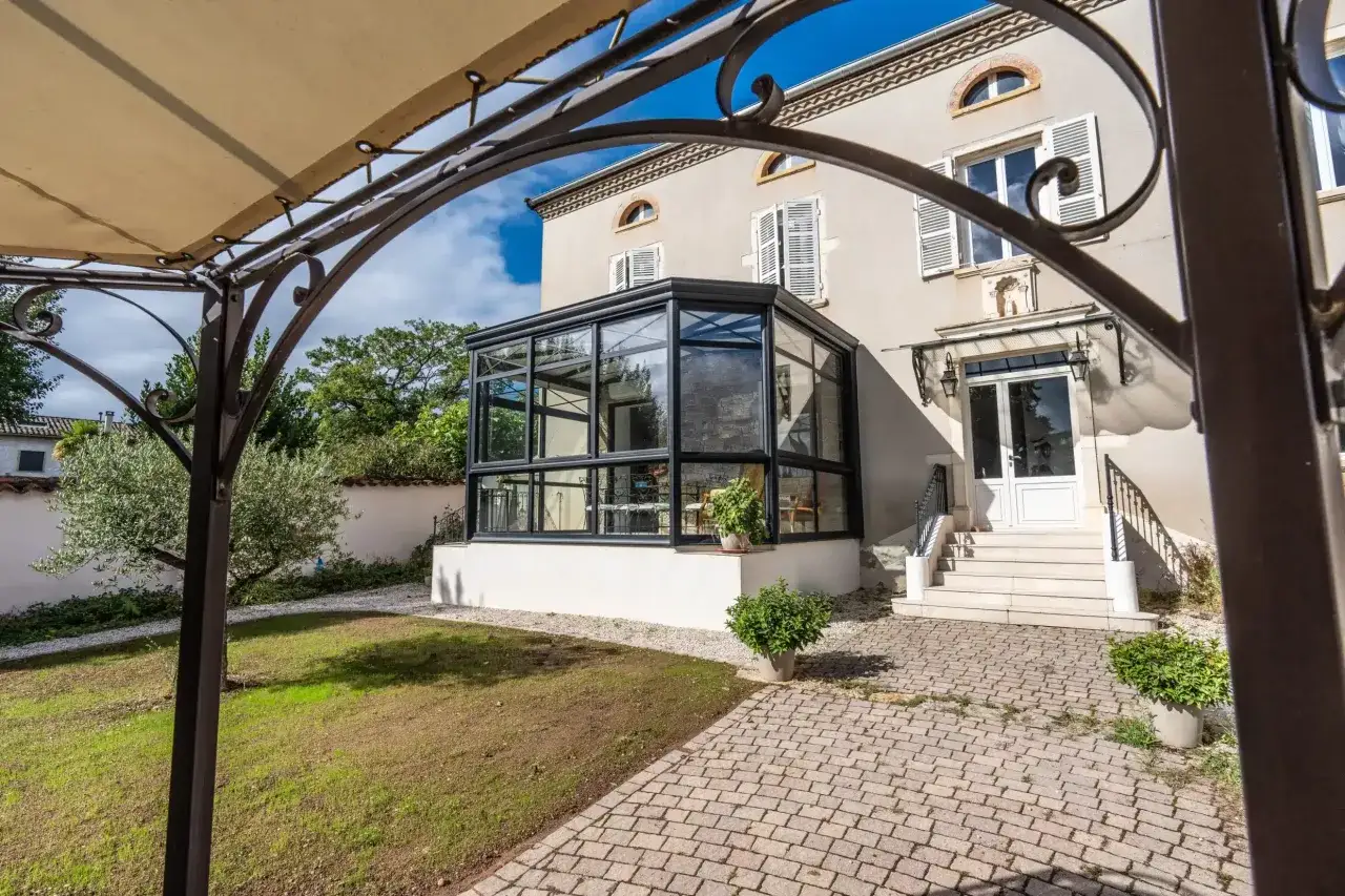 Maison avec véranda moderne et jardin. La taxe terrasse pourrait s'appliquer à cette extension vitrée.