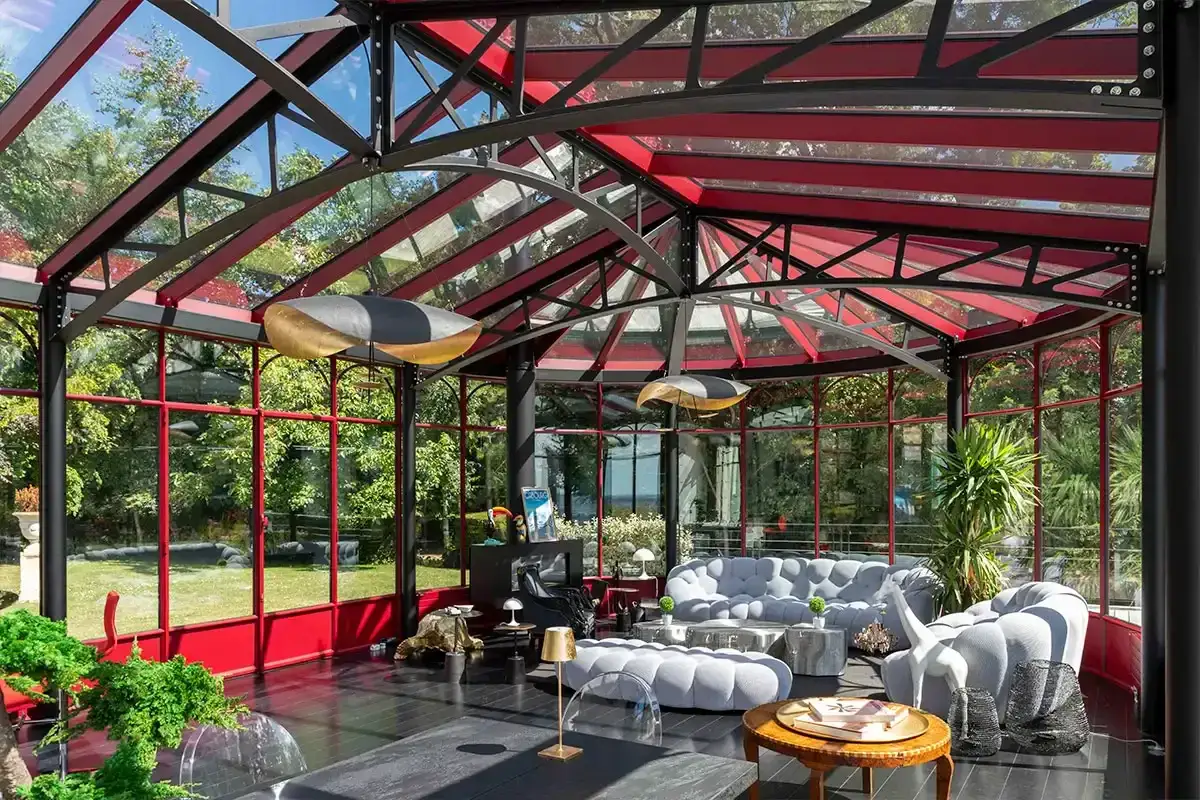 Un &eacute;l&eacute;gant jardin d'hiver verri&egrave;re avec des canap&eacute;s moelleux, des plantes luxuriantes et une vue imprenable sur la nature environnante.