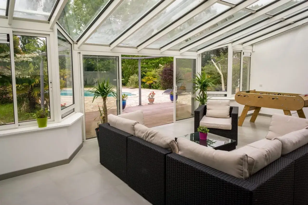 Vaste veranda 50m2 avec salon, baby-foot et vue sur piscine. Id&eacute;al pour se d&eacute;tendre et s'amuser en famille.