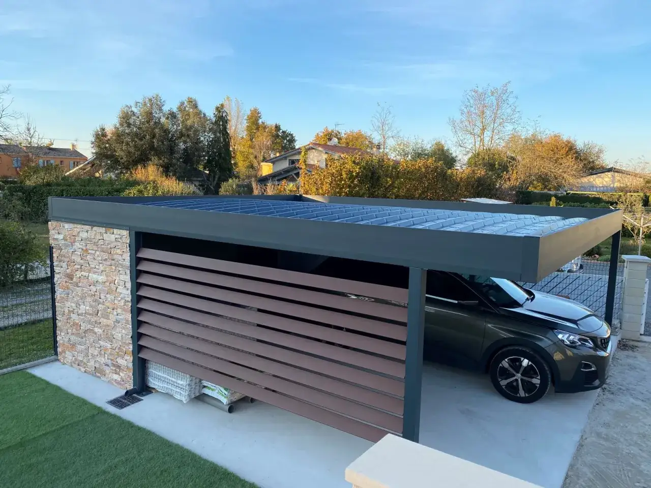 Un carport moderne avec un toit plat, id&eacute;al pour comment couvrir un carport toit plat. Une voiture est gar&eacute;e &agrave; l'int&eacute;rieur.