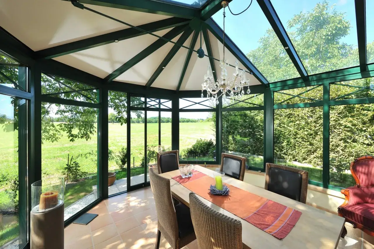 Une &eacute;l&eacute;gante veranda demi ronde avec un lustre en cristal, une table dress&eacute;e pour le d&icirc;ner et une vue imprenable sur la campagne verdoyante.
