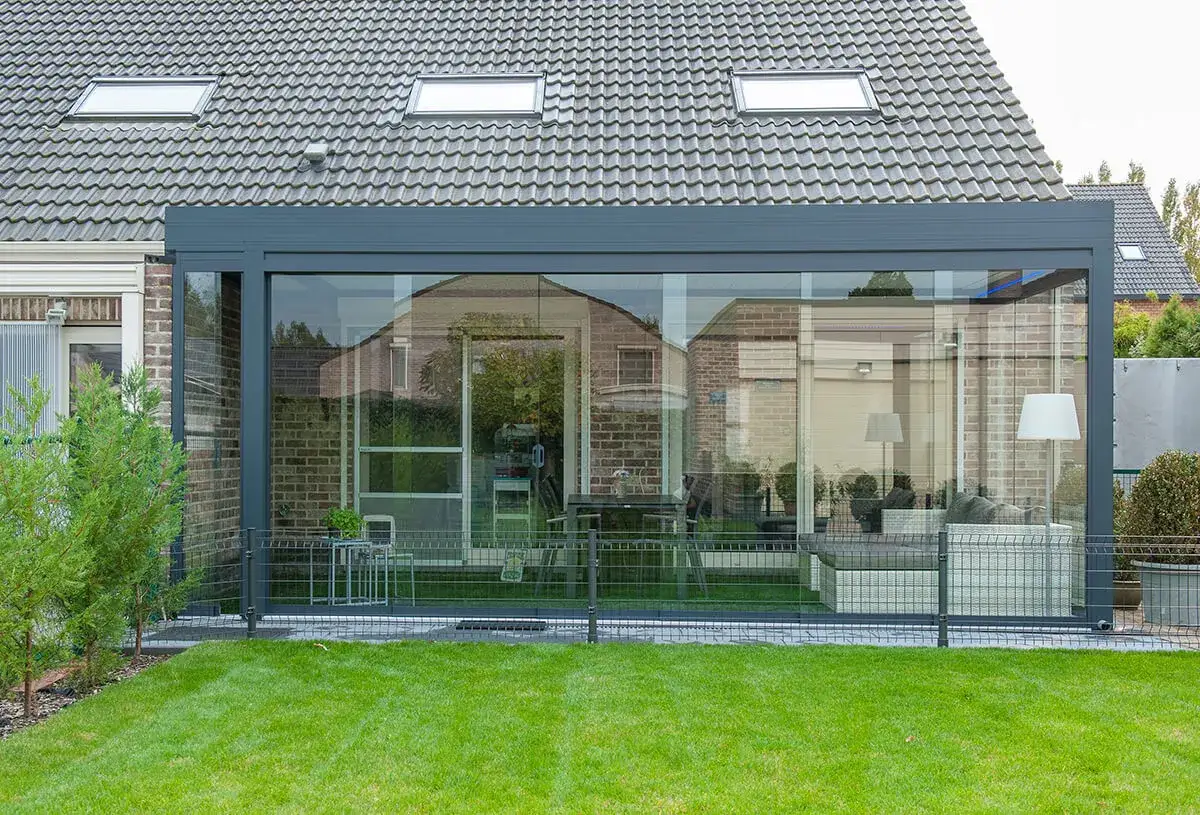 Une v&eacute;randa bioclimatique moderne avec de grandes baies vitr&eacute;es, un salon confortable et une table &agrave; manger. Avis : un espace lumineux et agr&eacute;able.
