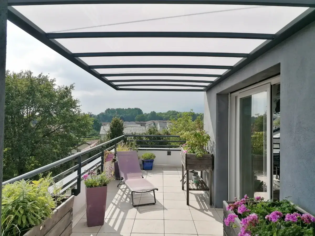 Terrasse avec auvent moderne, id&eacute;al pour la construction d'un auvent sans permis de construire. Transats et plantes invitent &agrave; la d&eacute;tente.