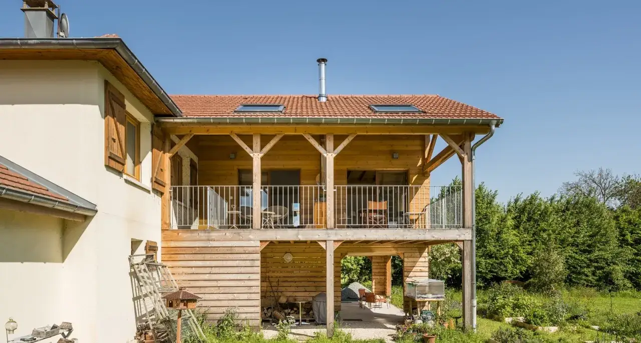Extension en bois sur pilotis, avec balcon et terrasse aménagée. Un bel espace de vie extérieur.