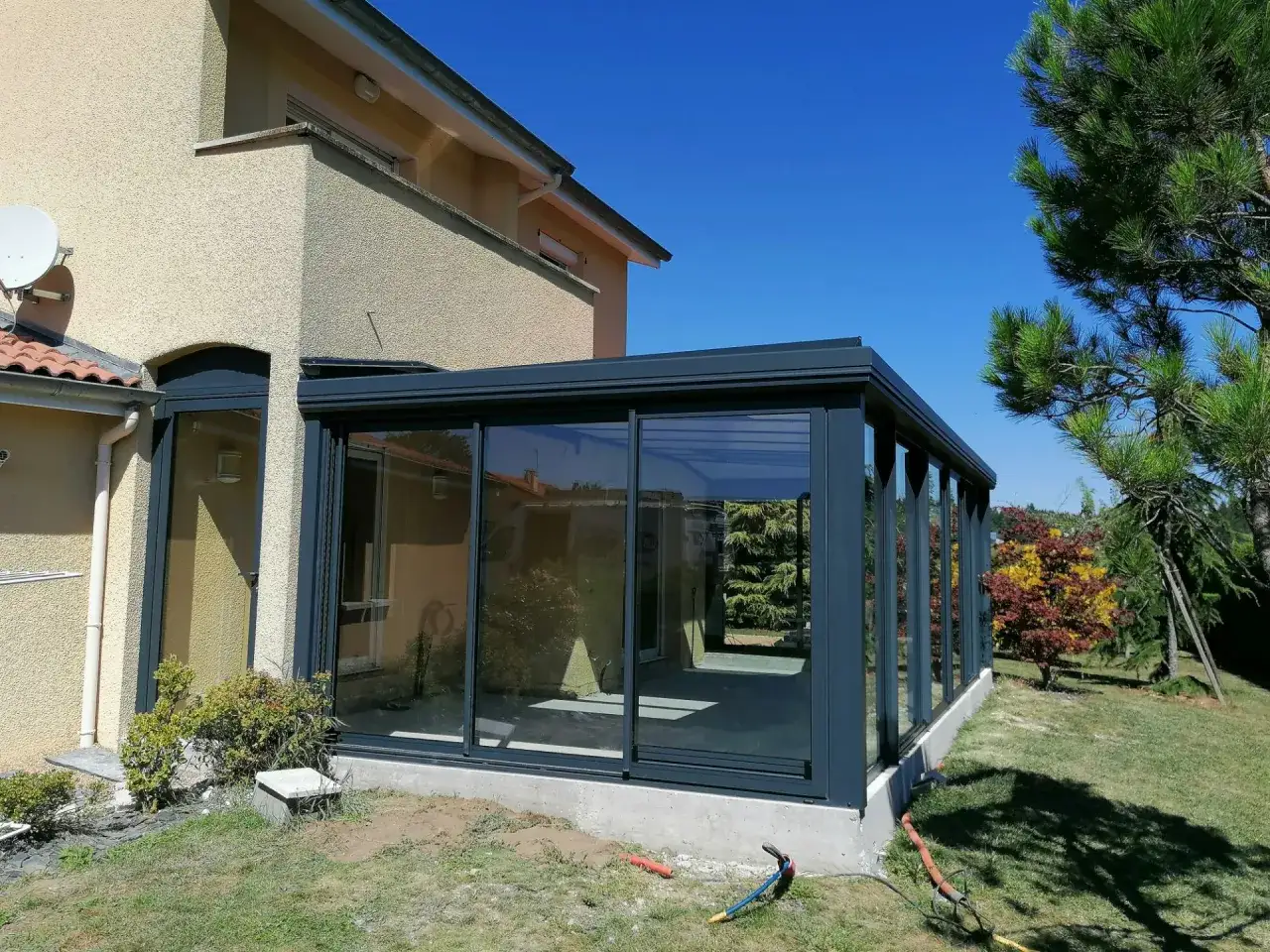 Dalle pour veranda moderne en verre et métal, s'intégrant parfaitement à la maison et au jardin.