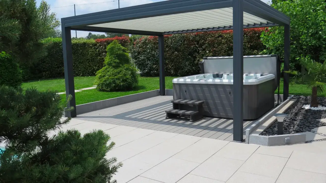 Construction d'une pergola moderne abritant un jacuzzi, avec un am&eacute;nagement paysager soign&eacute; et une terrasse en bois et pierre.