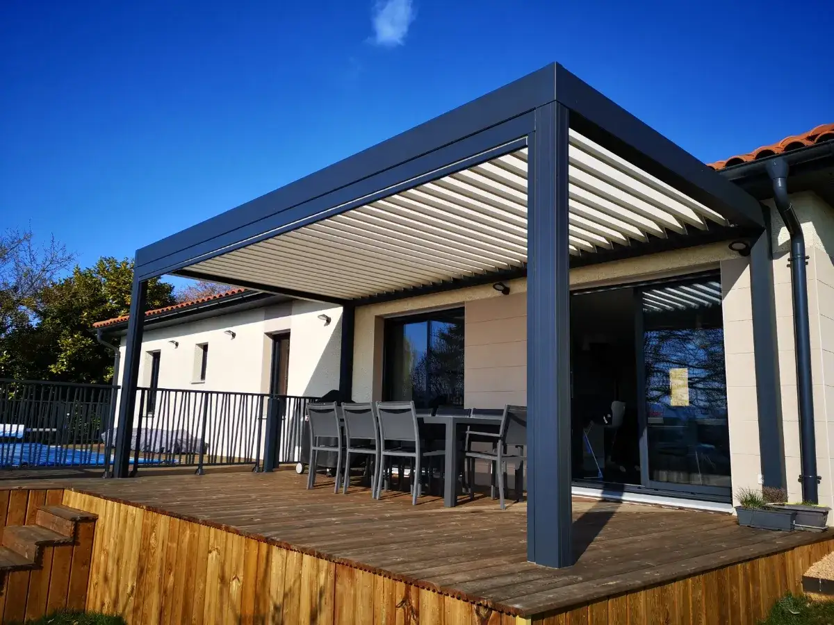 Pergola bioclimatique moderne sur terrasse en bois, avec lames orientables pour un confort optimal. Idéal pour savoir comment choisir une pergola bioclimatique.
