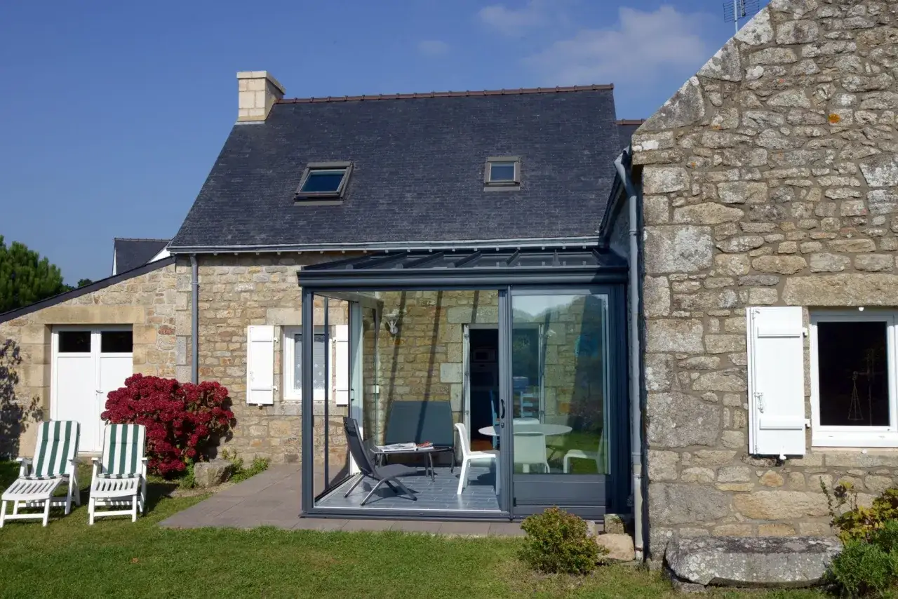 Une extension verri&egrave;re moderne s'int&egrave;gre parfaitement &agrave; cette maison ancienne en pierre, offrant un espace lumineux avec vue sur le jardin.