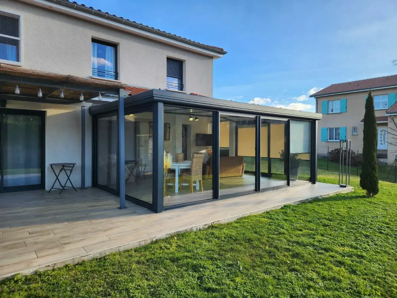 Veranda moderne en verre et métal, prolongeant une maison. Un espace lumineux avec salon et salle à manger, prêt pour une extension de votre habitation. Pensez à la taxe d'aménagement veranda.