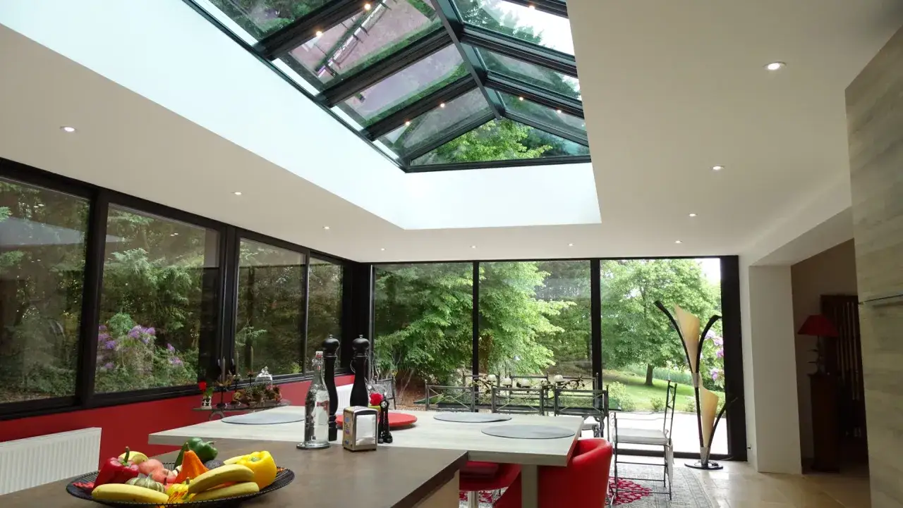 Int&eacute;rieur lumineux avec une cuisine moderne et une veranda triple vitrage offrant une vue imprenable sur un jardin luxuriant.