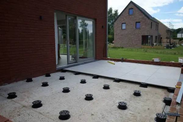 Installation de la dalle pour veranda sur des plots réglables. Le sol est en cours d'aménagement.
