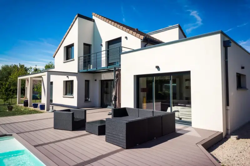 Une maison moderne avec une extension spacieuse, une terrasse en bois et une piscine. L'ensemble évoque une transformation réussie : extension maison avant après.